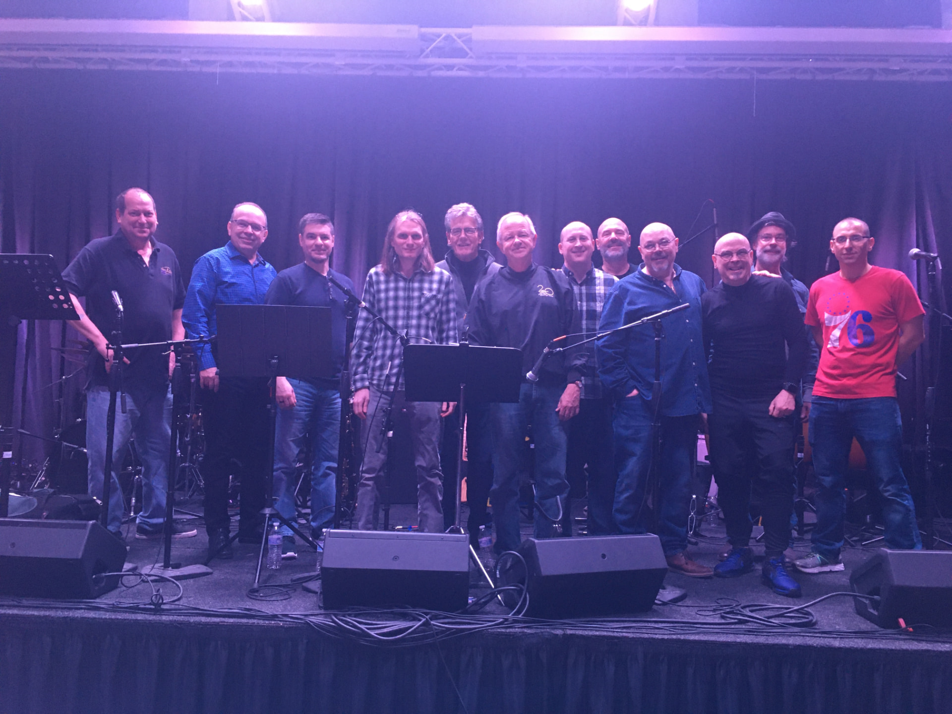 All twelve members of the Dance Hall Docs standing together on stage